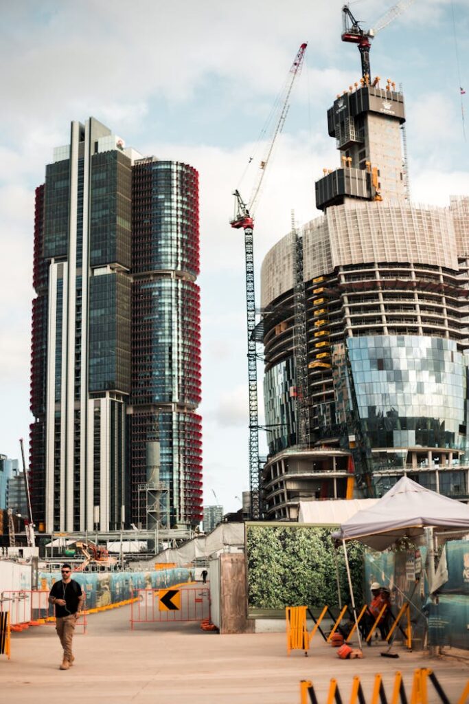 A dynamic city scene with skyscrapers and cranes under a bright sky.